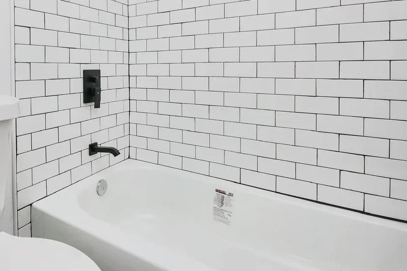A second bathroom finished in white 3x6 subway tile with black tub fixtures