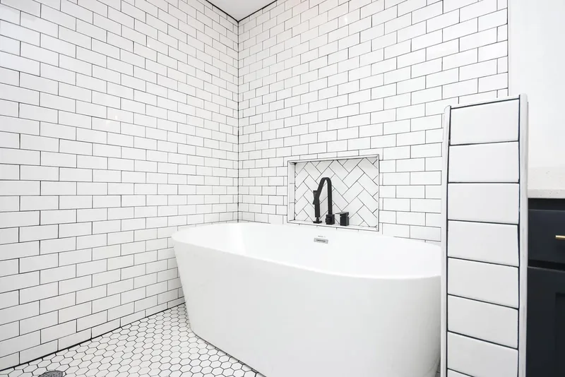 Primary bathroom with a freestanding soaking tub, subway tile, and a herringbone niche