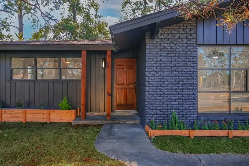 Board-and-batten and brick front entry with a solid wood door on a custom home by Green and Co.