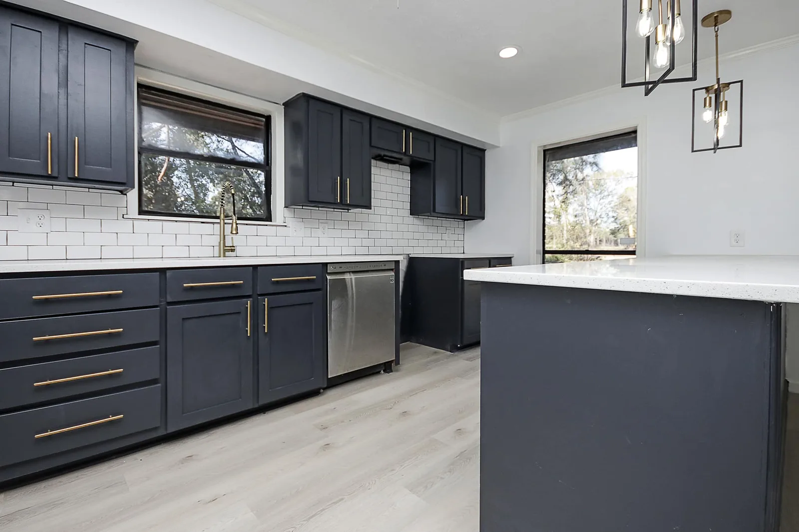 Navy shaker kitchen cabinets with gold pulls, subway backsplash, and stainless appliances