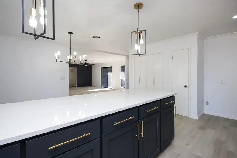 Custom kitchen with navy cabinetry, brass hardware, and a waterfall quartz island open to the dining area